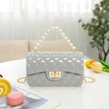 Grey quilted jelly bag with pearl handle and gold chain strap on decorative tabletop - Gray