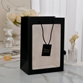 Vertical matte black gift bag with a large clear window and a golden tag detail - Black