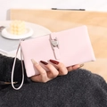 Close-up of pink long PU leather wallet with heart-shaped buckle and wrist strap - Pink