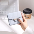 Primo piano di un portafoglio blu a tre ante con chiusura a foglia dorata in un caffè - Celeste