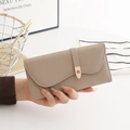 Detail of light brown PU clutch featuring a wavy flap and metal flower buckle detail - Camel