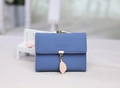 Close-up of blue tri-fold wallet with gold clasp and decorative pink leaf pendant detail - Sapphire Blue