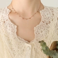 Collana romana in oro rosa con ciondoli a occhio indossata su top in pizzo - Stile Occhio Oro Rosa