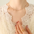 Elegant 18K rose gold necklace with polished teardrop pendants on a beige lace background - Rose Gold Water Drop Style