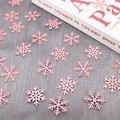 Detailed macro view of pink glitter snowflake confetti on dark wood background - Pink Glitter