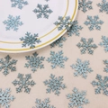 Close-up of sparkling light blue glitter snowflake confetti on a white ceramic plate - Light Blue Glitter