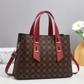 Classic monogram tote bag with gold patterns and red leather handles on a white pedestal - Coffee And Red