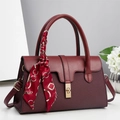 Close-up of burgundy pillow bag featuring woven texture, gold lock, and silk scarf detail - 30x12x18cm / Red