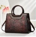 Detail der Blumenprägung auf braun-roter Vintage-Handtasche mit Farbverlauf - Weinrot