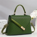 Detail of green satchel showing textured lettering, top handle and gold twist-lock closure - Green