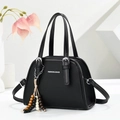Detailed macro view of black textured fabric handbag with white text logo and wooden tassel - Black