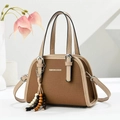 Brown canvas Boston handbag with beige leather trim and wooden bead charm on a white desk - Brown