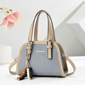 Close-up of blue denim small handbag with beige leather trim and colorful bead charm - Blue