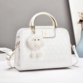Detail of white glossy handbag with triangular texture, gold handle and plush charm - Pure White