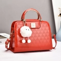 Detail der roten Lackledertasche mit Dreiecksprägung und goldener Vogelschließe - Rot