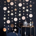Close-up of glittery rose gold star and circle garland hanging in festive indoor setting - Champagne Gold