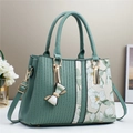 Elegante borsa a mano verde menta con stampa floreale e dettagli dorati su sfondo neutro - Verde