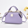 Lila Boston-Tasche mit Litschimuster, Goldbeschlägen und Vogel-Logo auf weißem Grund - Lavendel