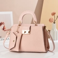 Close-up of pink lizard texture handbag with gold twist lock and mini charm pouch - Pink