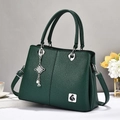 Detalle de bolso verde oscuro en cuero lichi con logo de pájaro y colgante metálico - Verde / 30x13x21cm