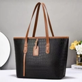 Bolso tote negro con textura de cocodrilo y asas marrones en ambiente de estudio chic - Negro