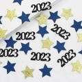 Close-up of 2023 number confetti with gold glitter stars and blue paper stars decor - Blue Gold Star and Black 2026 Confetti
