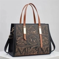 Close-up of bronze embroidery with bird and floral patterns on black leather tote bag - Black