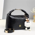 Detalle del bolso de charol negro con textura de cocodrilo, logo dorado y peluche - Negro