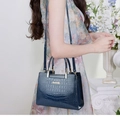 Detail of dark blue crocodile pattern embossed leather handbag with gold metal logo - Blue