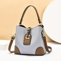 Close-up of light blue and brown bucket bag showing lychee texture and metal D-ring - Blue