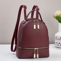 Detail eines weinroten Lederrucksacks mit goldenen Reißverschlüssen und zwei Fächern - 24x12x29cm / Rot