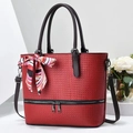 Detail of red woven bucket tote bag with black handles and colorful printed silk scarf bow - Red