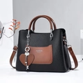 Fashion black leather tote bag with brown pocket and heart charm in a 45-degree side view - Black