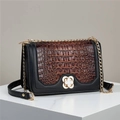 Crocodile texture crossbody bag with gold flower buckle on white platform display - Coffee
