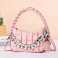 Pink quilted handbag with chunky silver chain detail and woven handle on orange background - Pink