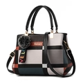 Detail view of plaid patterned handbag with plush ball pendant and gold logo - Black