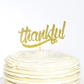 Sparkling gold glitter 'thankful' cake topper on a white cream cake for Thanksgiving party - thankful