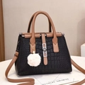 Schwarze Handtasche mit Krokodilmuster, braunen Griffen und weißem Plüsch-Anhänger - Schwarz