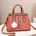 Detail of coral pink crocodile-pattern leather bag with plush ball charm and metal buckle - Pink
