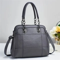 Close-up of grey leather tote bag featuring quilted pattern and metal chain handle - Gray