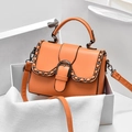 Orange lychee pattern crossbody bag with chain trim and D-ring buckle in a white box - Orange