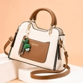 Bolso bandolera beige y marrón con asa superior y colgante de conejo verde - Blanco Roto