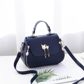 Dark blue litchi pattern handbag with a golden cat charm and pearl tassel detail - Blue