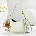 Detailansicht der cremeweißen Ledertasche mit Litschi-Struktur und breitem Gurt - Zweiteiliges Taschen-Set mit Anhänger / Weiß