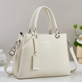 Detailansicht der cremeweißen Lederhandtasche mit silbernen Ringen und Mode-Aufdruck - Cremeweiß
