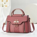 Elegant dusty pink handbag with swan metal buckle and pearl charm on a minimalist desk - Pink