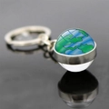 Porte-clés mappemonde en verre avec anneau en métal argenté sur surface réfléchissante - Terre Simulée Bleu Vert (JY006262-13)
