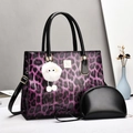 Detail of purple leopard print tote bag set with black patent leather trim and fur charm - Purple