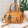 Detail of yellow Boston handbag featuring retro bronze rivets and decorative charms - Yellow