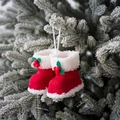 Pair of red and white quilted Christmas boot ornaments hanging on a snowy tree branch - Rhombus / Red